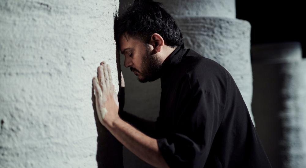 man leaning his head on a wall eyes closed