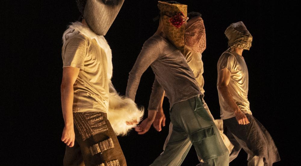 dancers with masks walk in a line