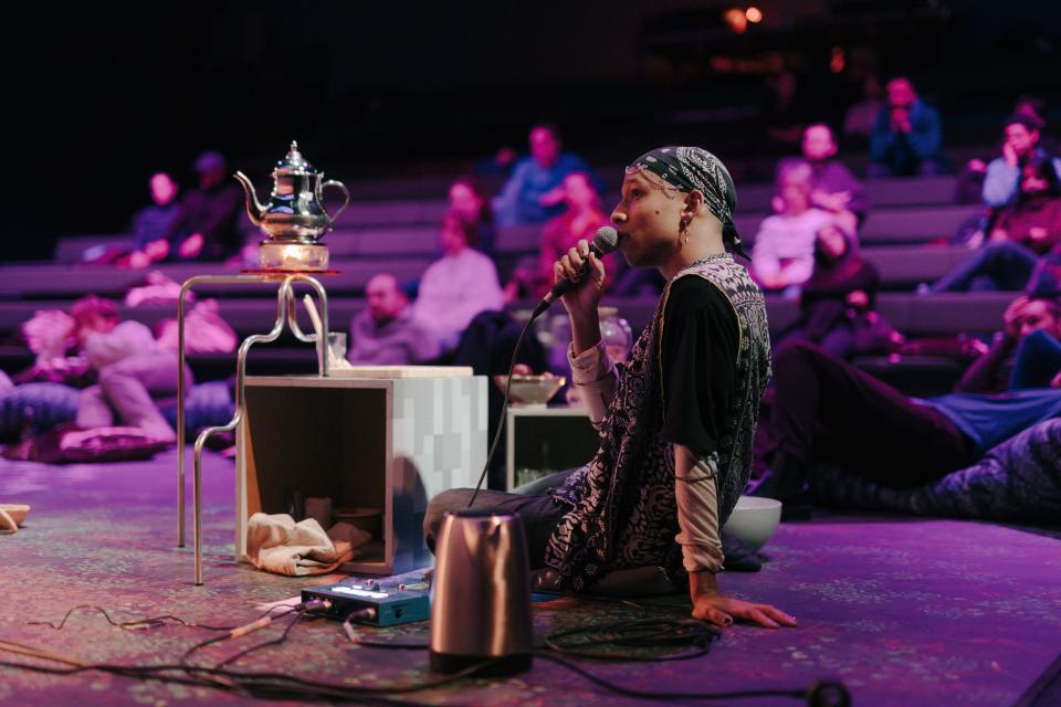 Person sitting on stage, talking in a microphone