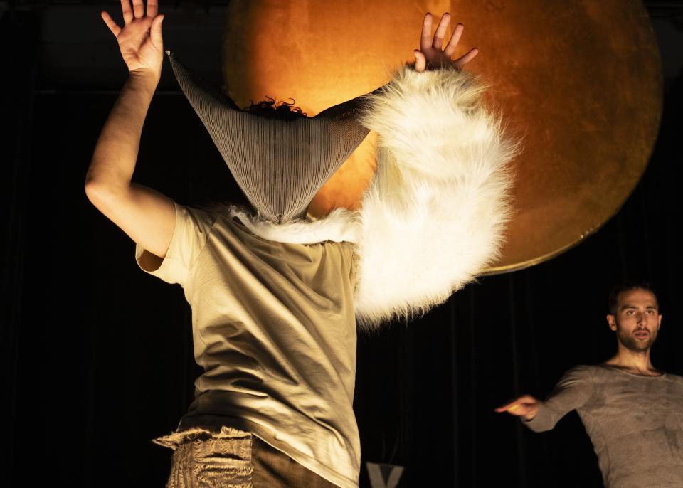 dancer with mask spreads arms